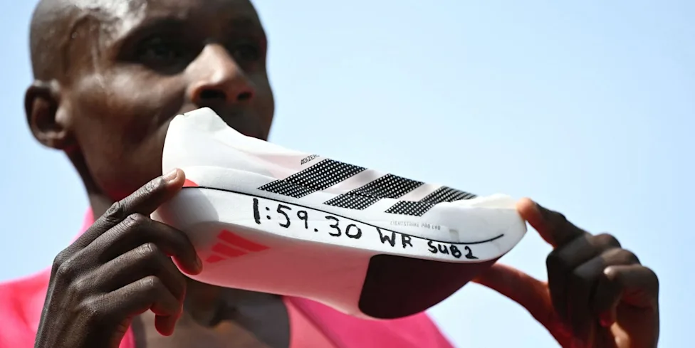 athlete holding a running shoe with notable writing